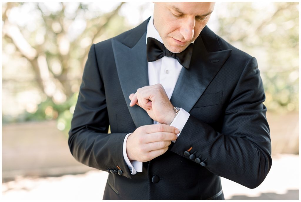 Groom in black and white suit adjusting cuffs