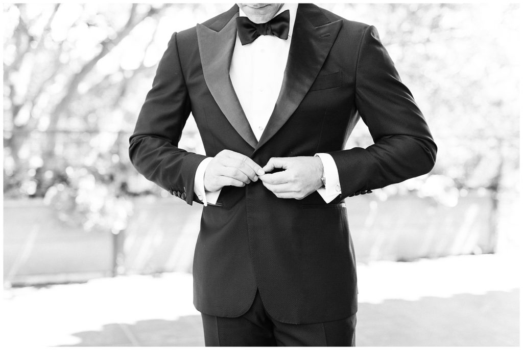 Groom buttoning his suit coat before wedding