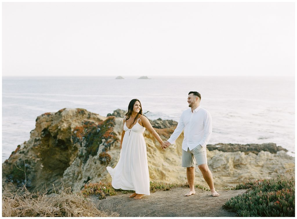 Hand in hand, the smiling couple wanders along a sandy path for their lovely engagement in Beautiful Big Sur