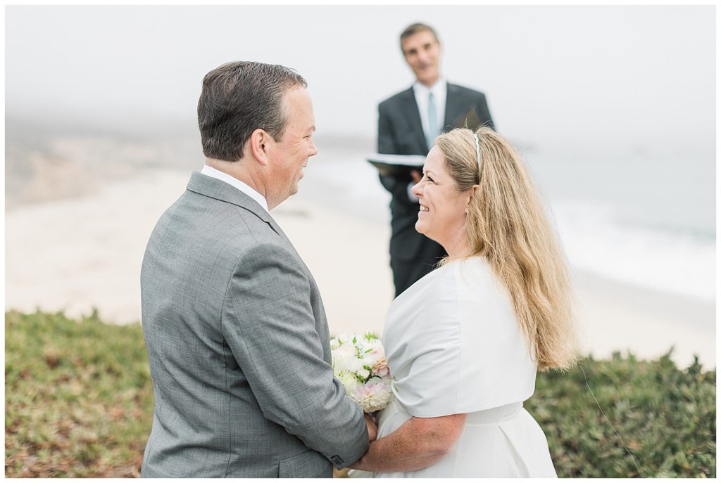 bride and groom smiling at one another with their Big Sur elopement officiant in the background by film photographer AGS Photo Art