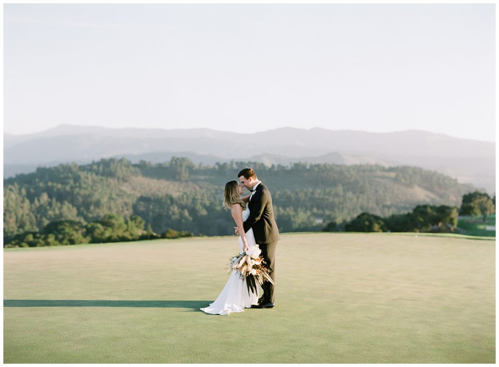 couple embracing in the middle of a large open golf field