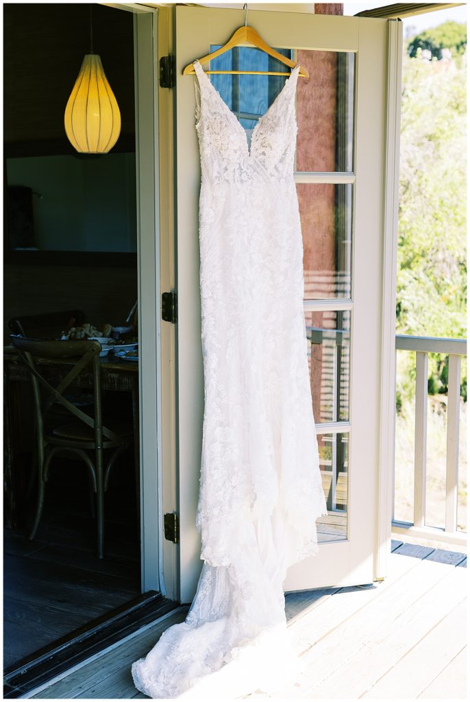 photo of bride's Big Sur elopement wedding dress hanging in the doorway at Bernardus Lodge & Spa by film photographer AGS Photo Art