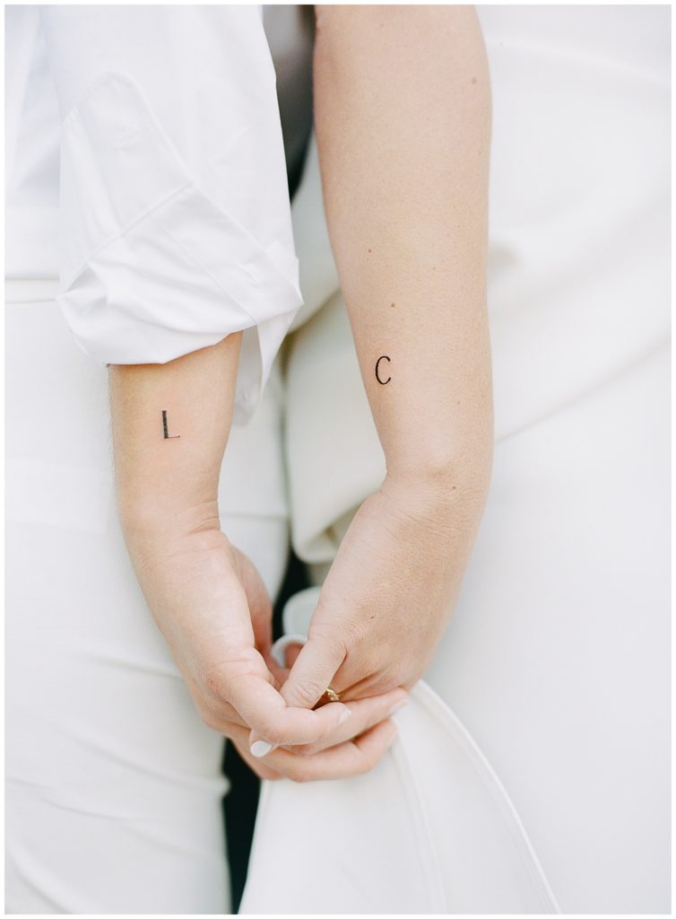 photo of two brides' hands intertwined with their wrists bearing tattoos of the first letter of each other's names by film photographer AGS Photo Art