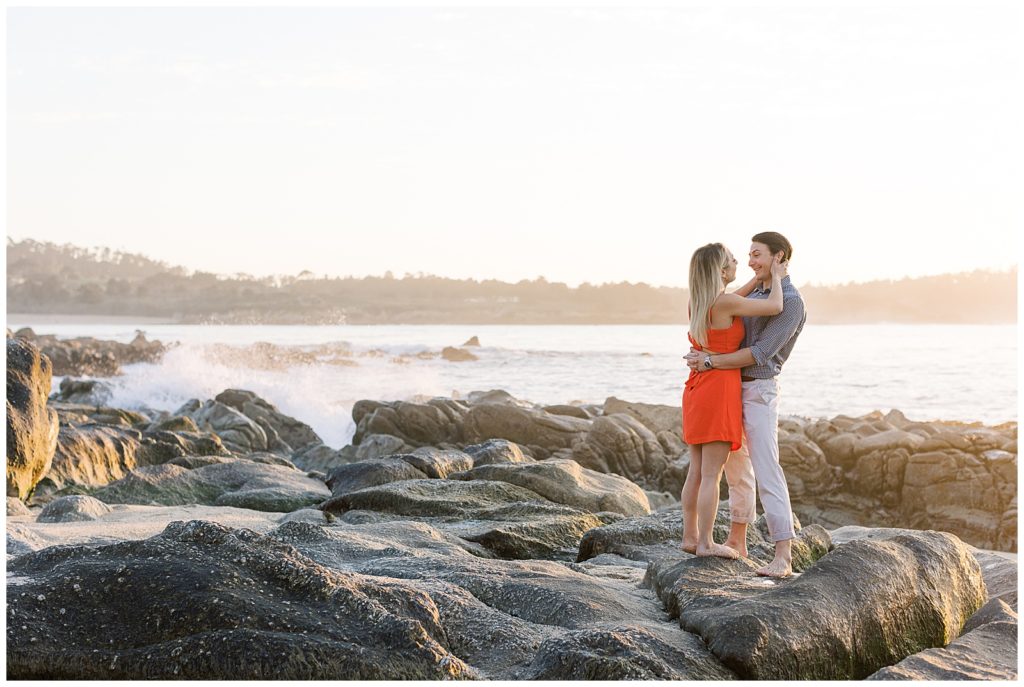 a portrait of a couple standing together on the rocks at the beach