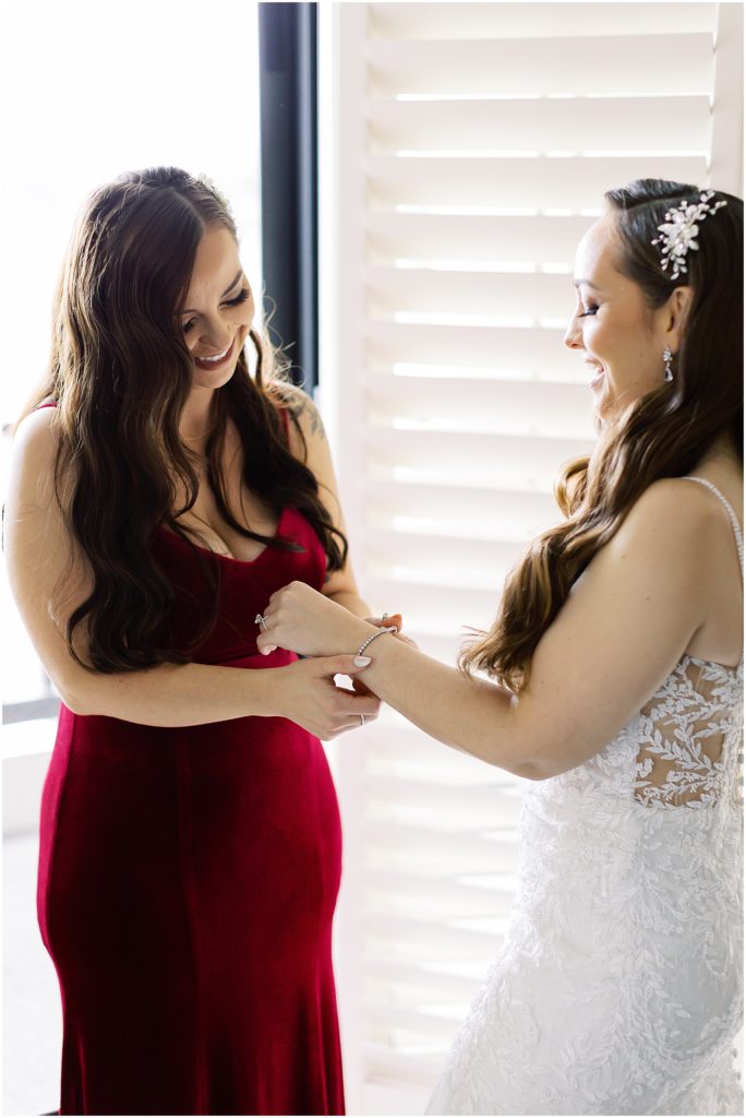 portrait of bridesmaid helping bride get ready by film photographer AGS Photo Art