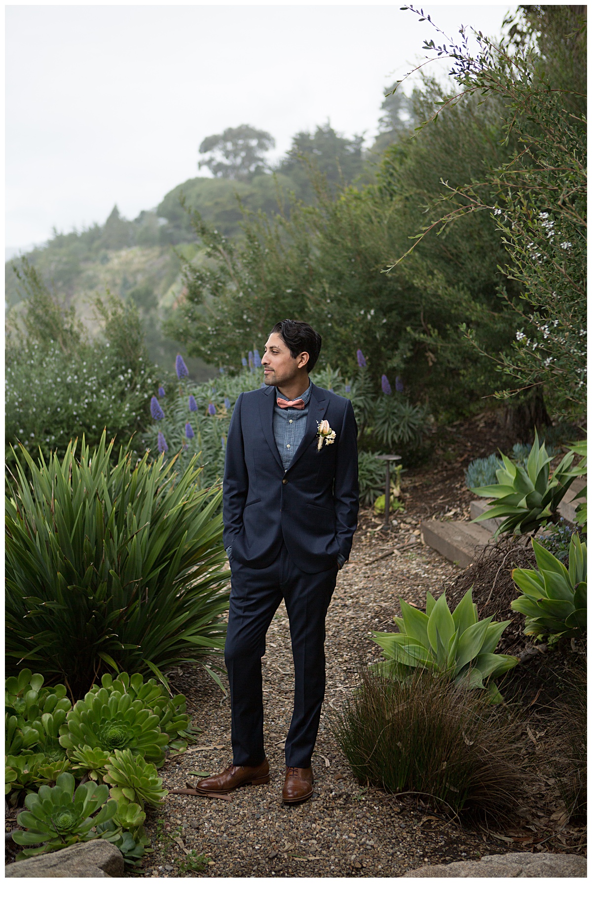 groom waiting for his bride to come down for a first look. Surrounded by California large succulents and dressed with a dark suite, denim under dress shirt and pink bowtie. He has a hipster vibe to him.
