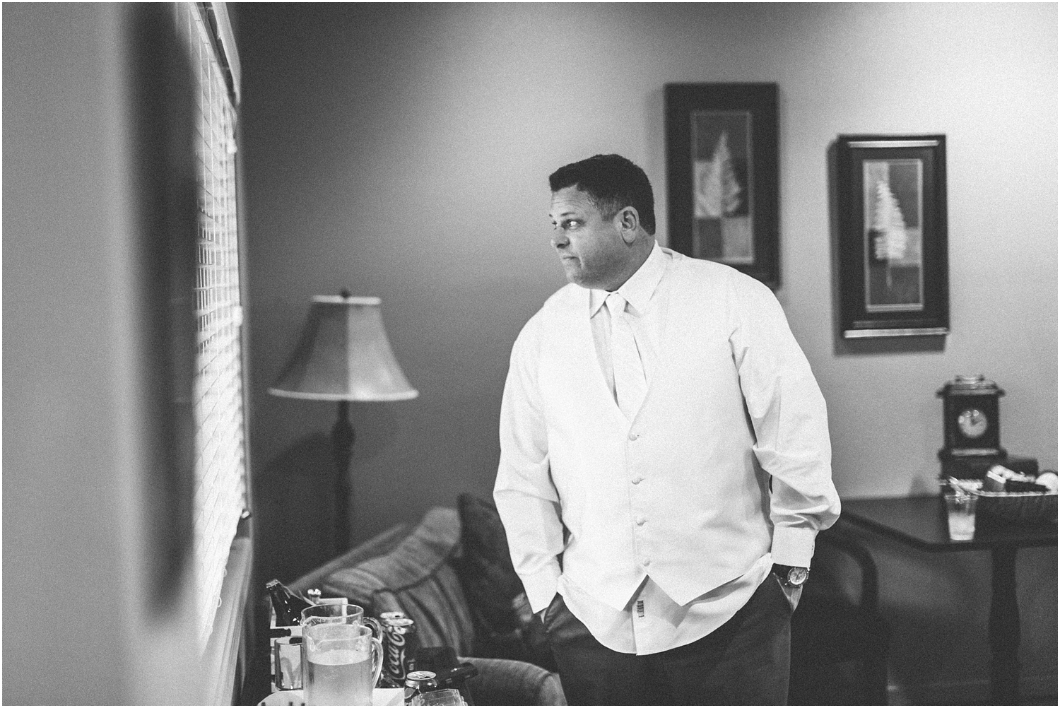 groom waiting patiently by the window for his bride black and white image