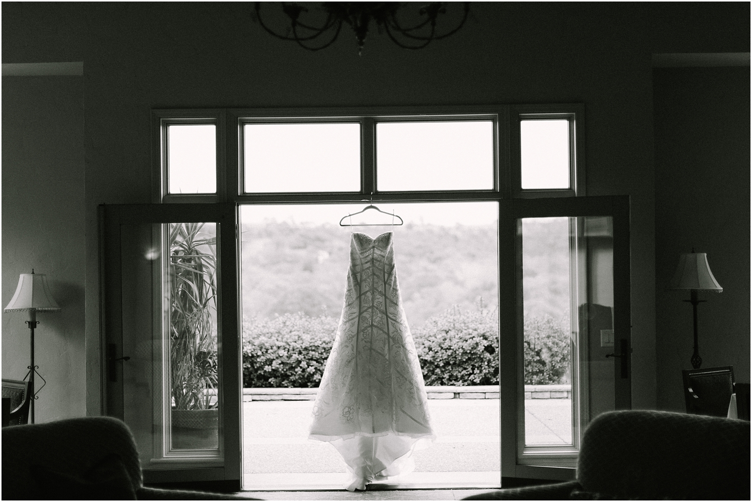 black and white image bridal gown hanging in the window 
