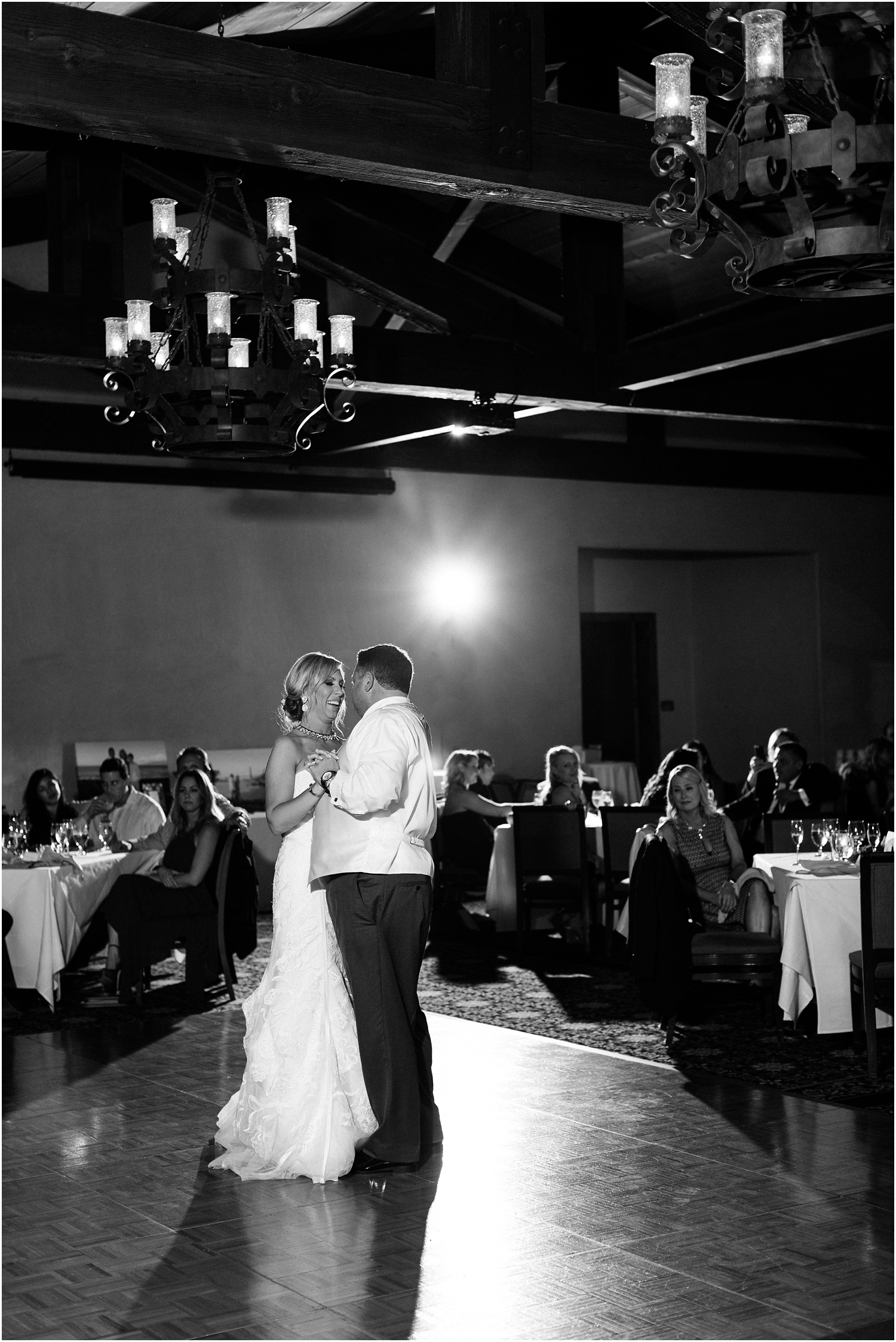 black and white first dance photo of bride and groom on reception floor smiling
