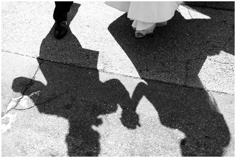 black and white photo of bride and groom walking downtown shadow image by AGS Photo Art