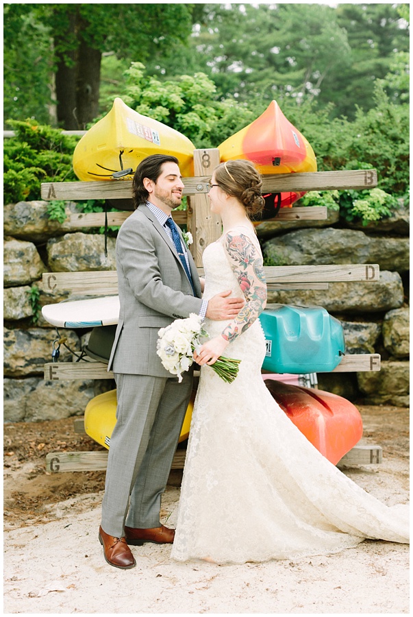 tattooed bride with groom in front of colorful kayaks at their Unique wedding in the Poconos