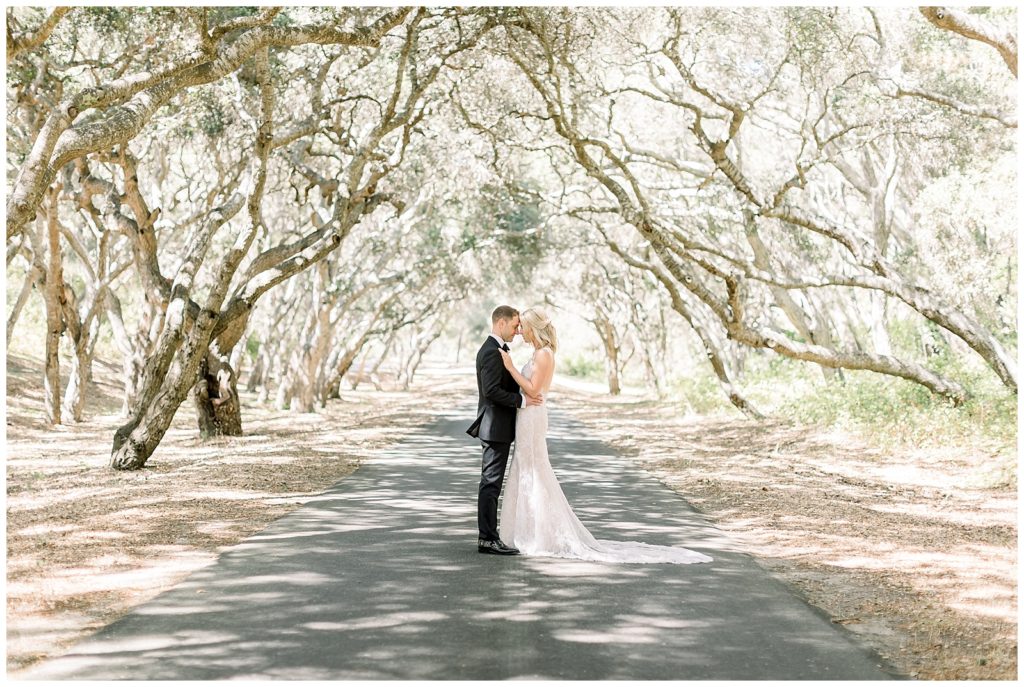 Bride and groom standing under oak tree canopy at Tehama Golf Club in Carmel, CA