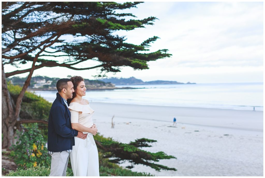 groom holding his bride while they look out at the shoreline