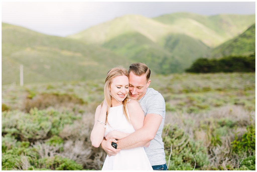 couple in each other's arms in a field with rolling hills