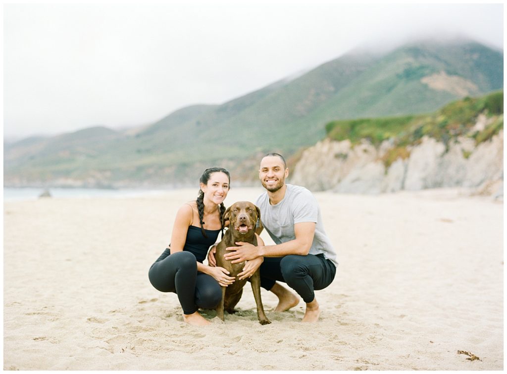 couple posing with their dog on the beach