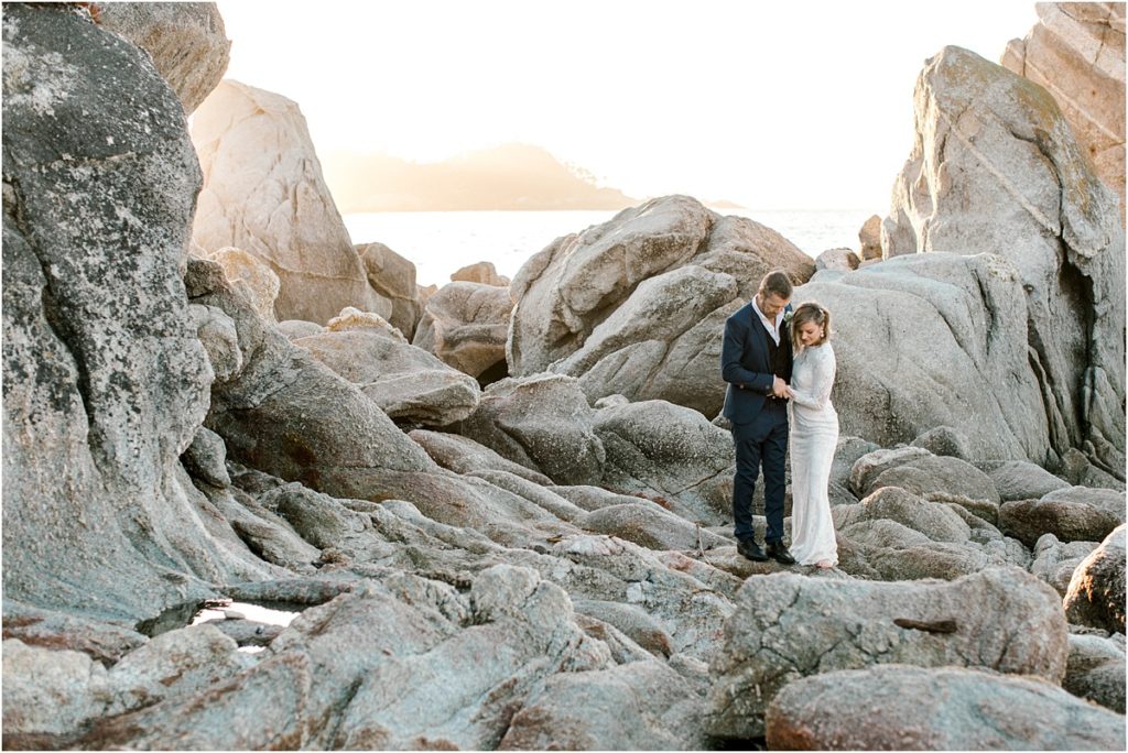 Couple adventuring on the rocks with the sun shining down on them.