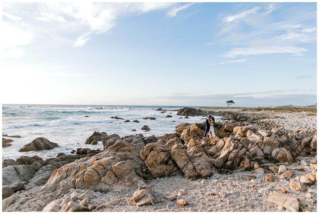 Beautiful Pebble Beach Engagement photo of coastal landscape with couple embracing on the rocky shoreline by film photographer Ags Photo Art