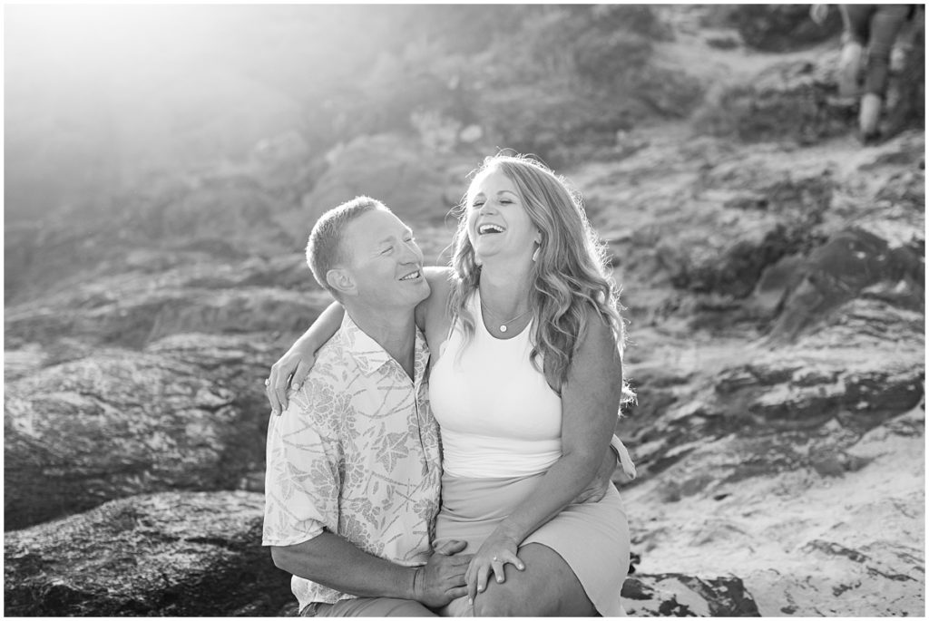 black and white image of a couple laughing on Carmel Beach after a surprise proposal