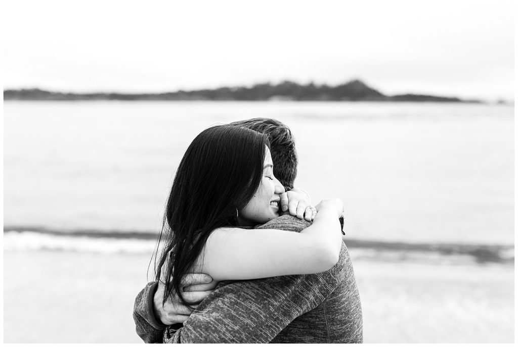 black and white portrait of the couple embracing at the beach