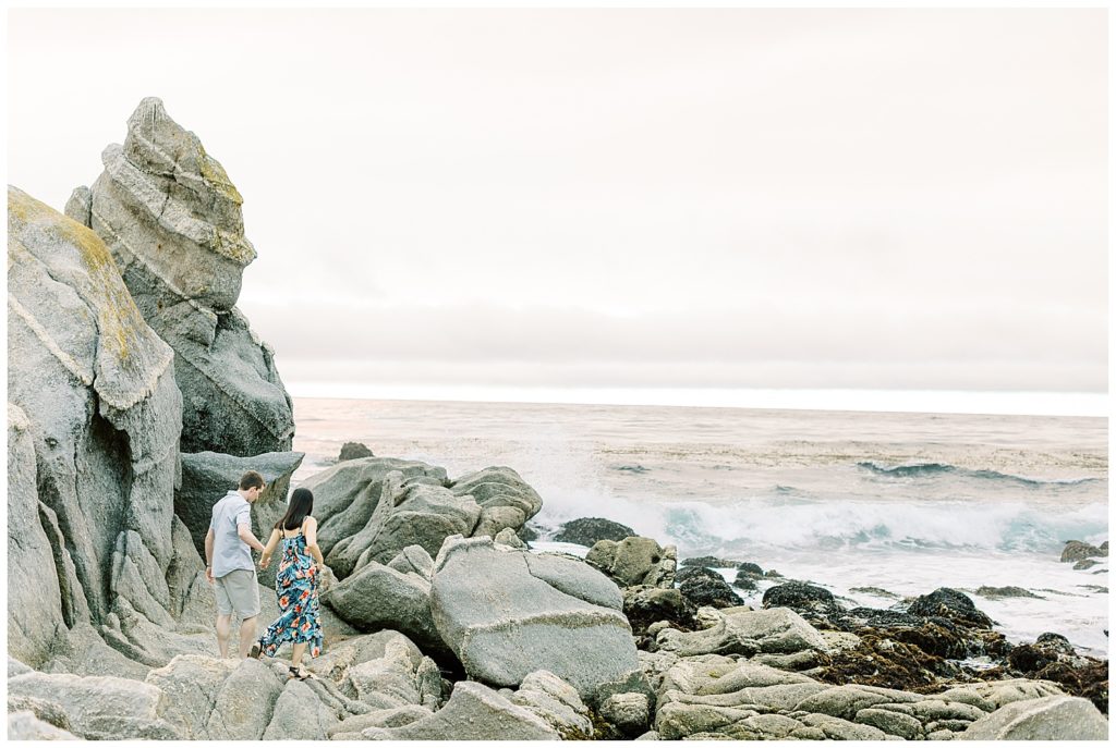 couple hand in hand exploring the rocks at Carmel by the Sea as the waves crash nearby by film photographer AGS Photo Art