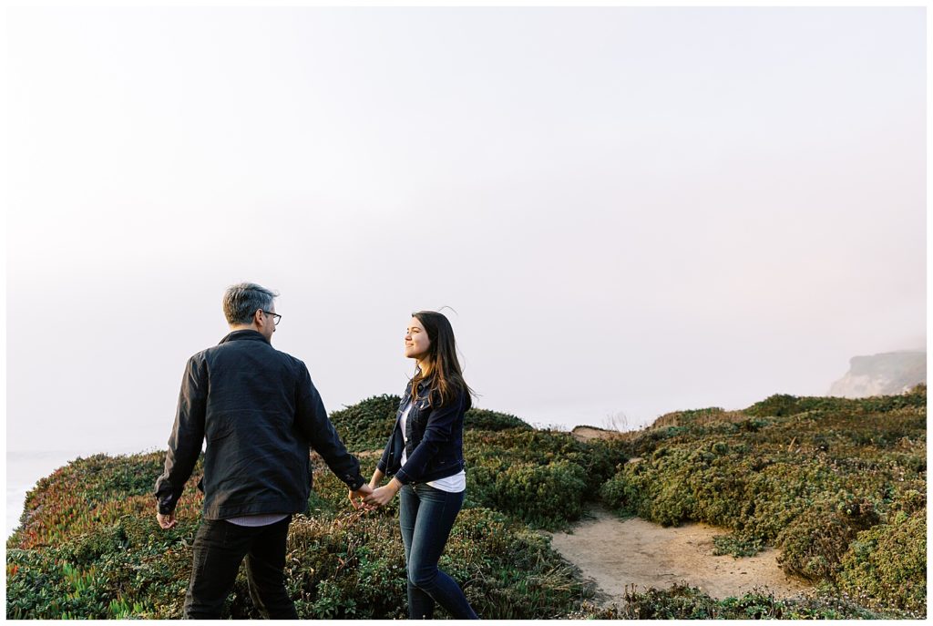 couple walking through greenery after their surprise proposal at Bixby Bridge in Big Sur, CA by film photographer AGS Photo Art
