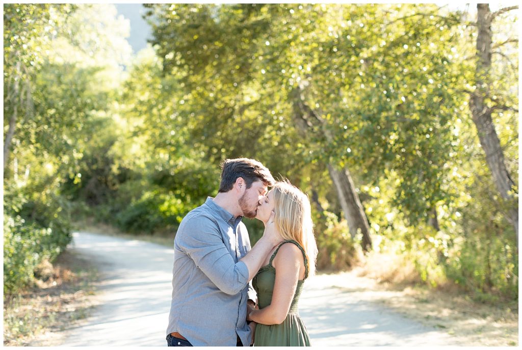 The couple sharing a kiss on an open road surrounded by sunshine-filled trees for their Powerful And Heartfelt Anniversary Session in Carmel, CA by film photographer AGS Photo Art