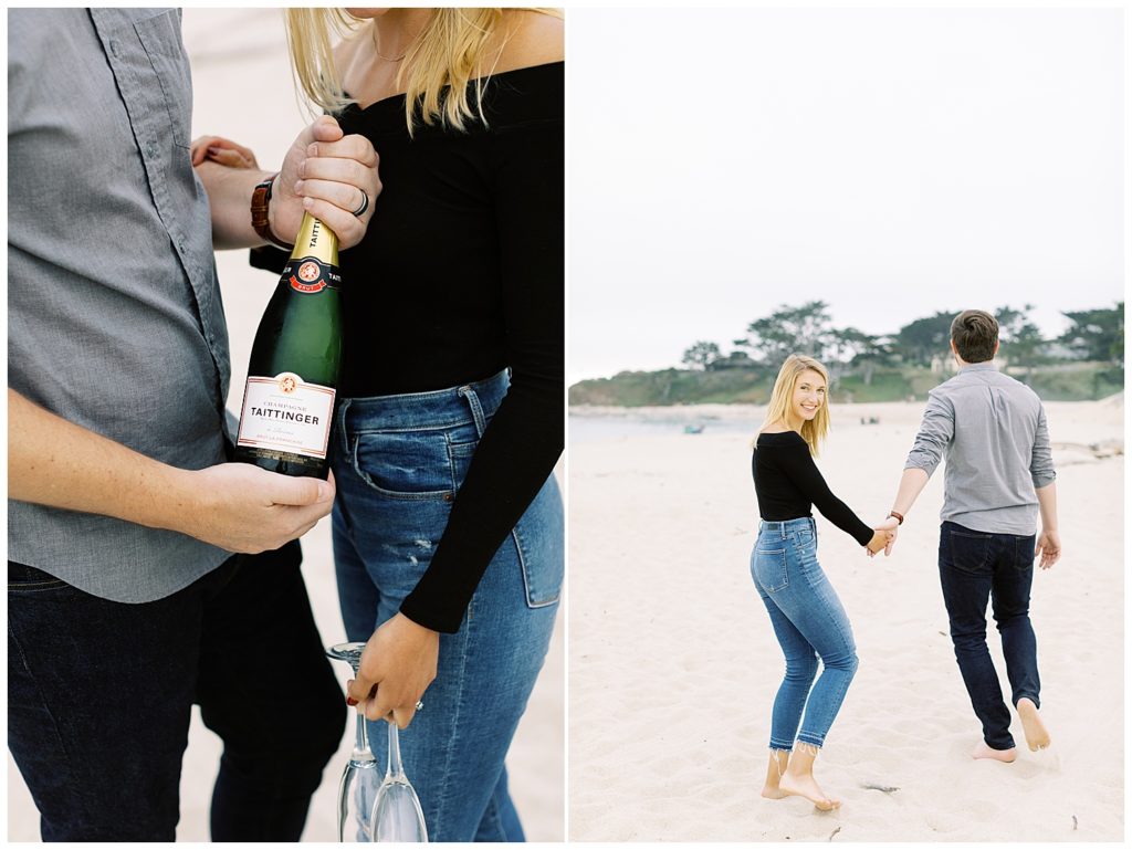 The couple prepares to enjoy a bottle of their favorite Tattinger Champagne for their Powerful And Heartfelt Anniversary Session on the white sands of Carmel Beach; the woman glances back at the camera smiling while her husbands leads the way forward