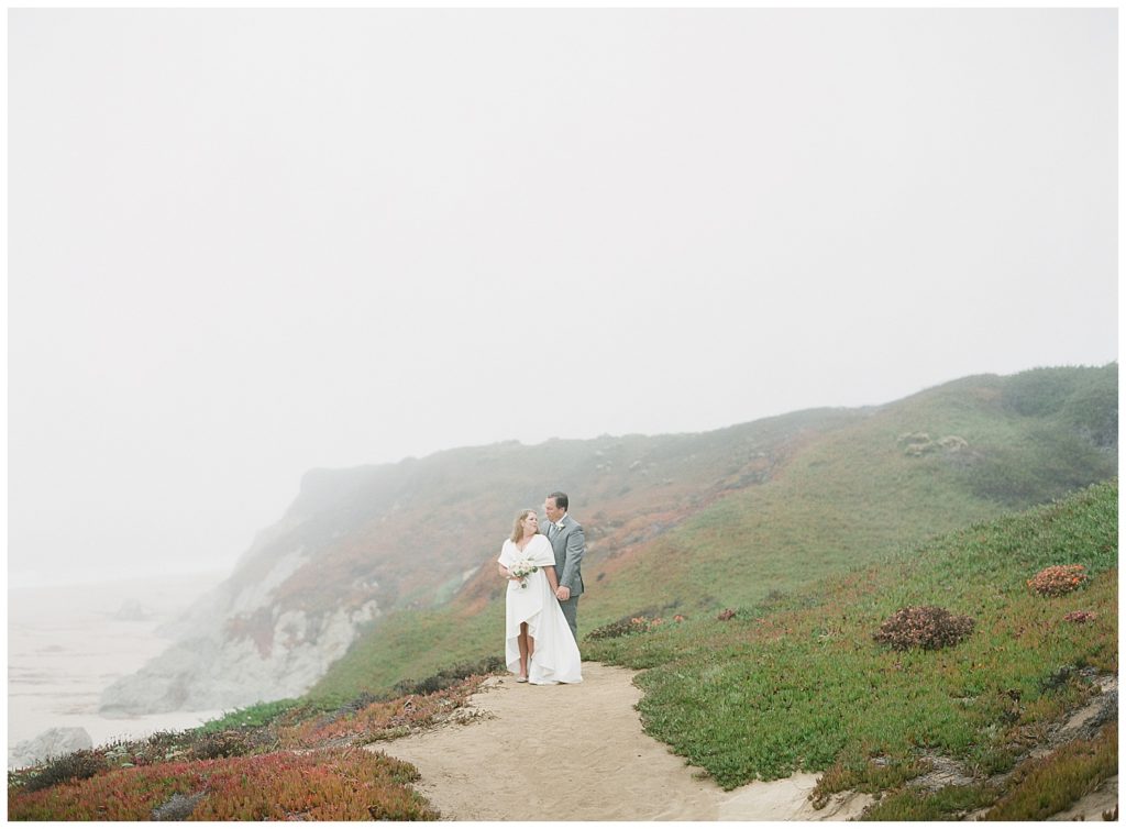 photograph of the bride and groom on the green and white sandy cliffs of Big Sur, CA for their elopement