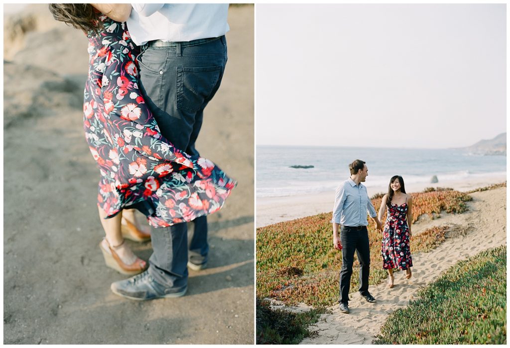 Big Sur Surprise Proposal photo of couple from the waist down; the woman in a blue floral dress and brown wedges, her fiancé in dark jeans and black shoes; portrait of the couple walking down a sandy path