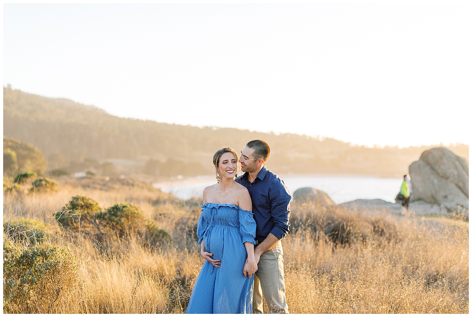 landscape portrait of new soon to be parents dressed in blue standing in a golden field by film photographer AGS Photo Art