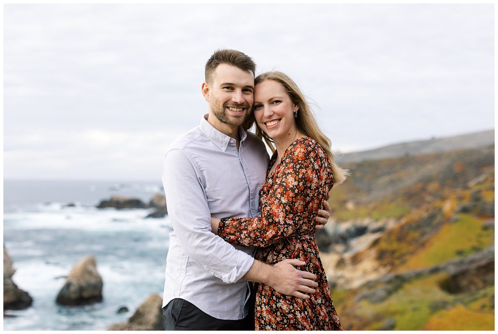 couple smiling at the camera while embracing each other during their Big Sur Sunset Engagement Shoot by film photographer AGS Photo Art