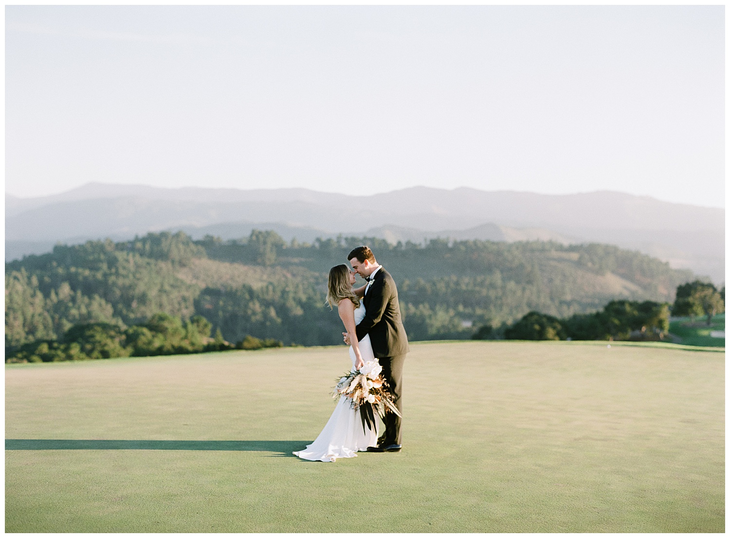 couple embracing in the middle of a large open golf field