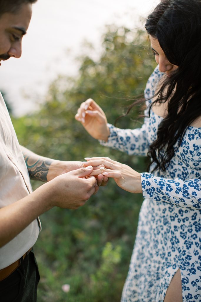 man sliding engagement ring onto his fiancée's finger