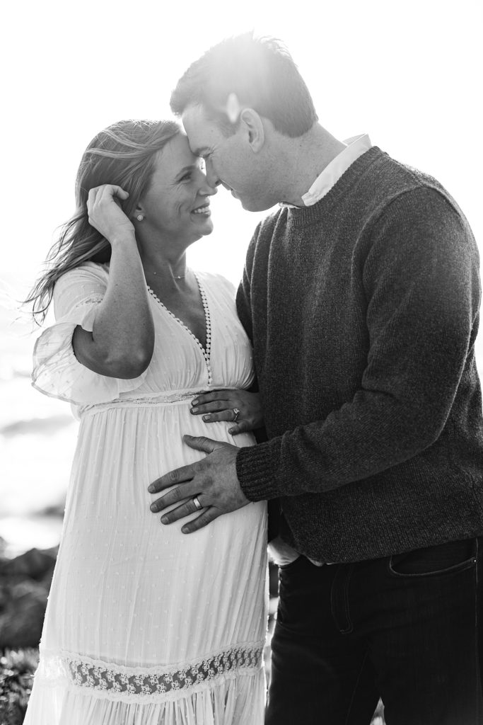 Big Sur maternity session black and white portrait of the couple smiling at each other with their hands on the baby bump