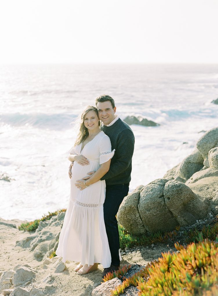 Big Sur couple portrait maternity session on the cliffside with foamy white ocean waves behind them