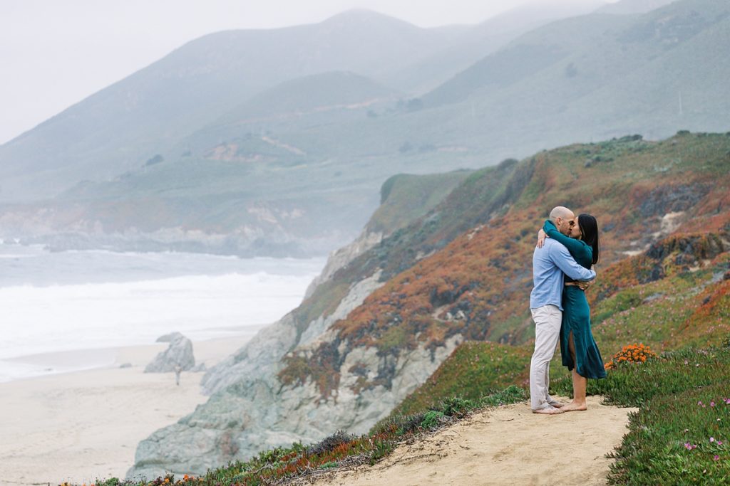 couple sharing a kiss on the cliffside in Big Sur at Garrapata Beach for their proposal by film photographer AGS Photo Art