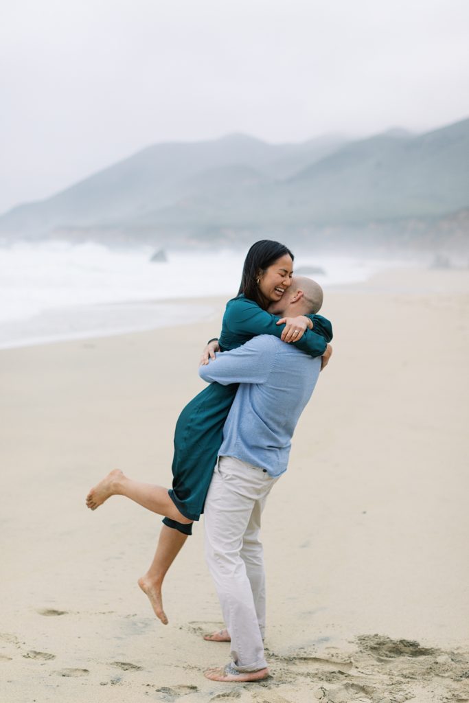 woman jumping into her fiance's arms after their Big Sur Garrapata Beach proposal by film photographer AGS Photo Art