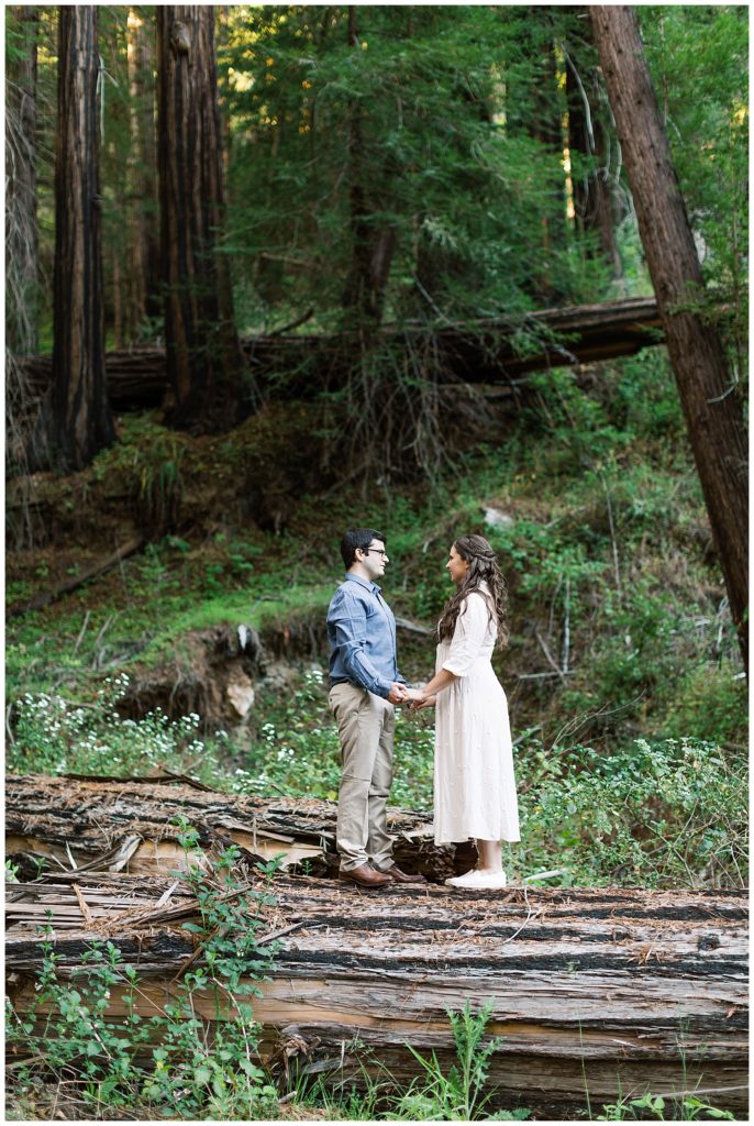 couple holding hands and facing each other surrounded by the forest