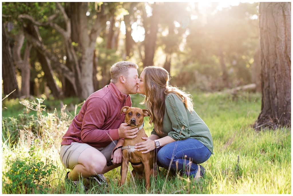 couple sharing a kiss during their Pebble Beach engagement in the forest with their dog by film photographer AGS Photo Art