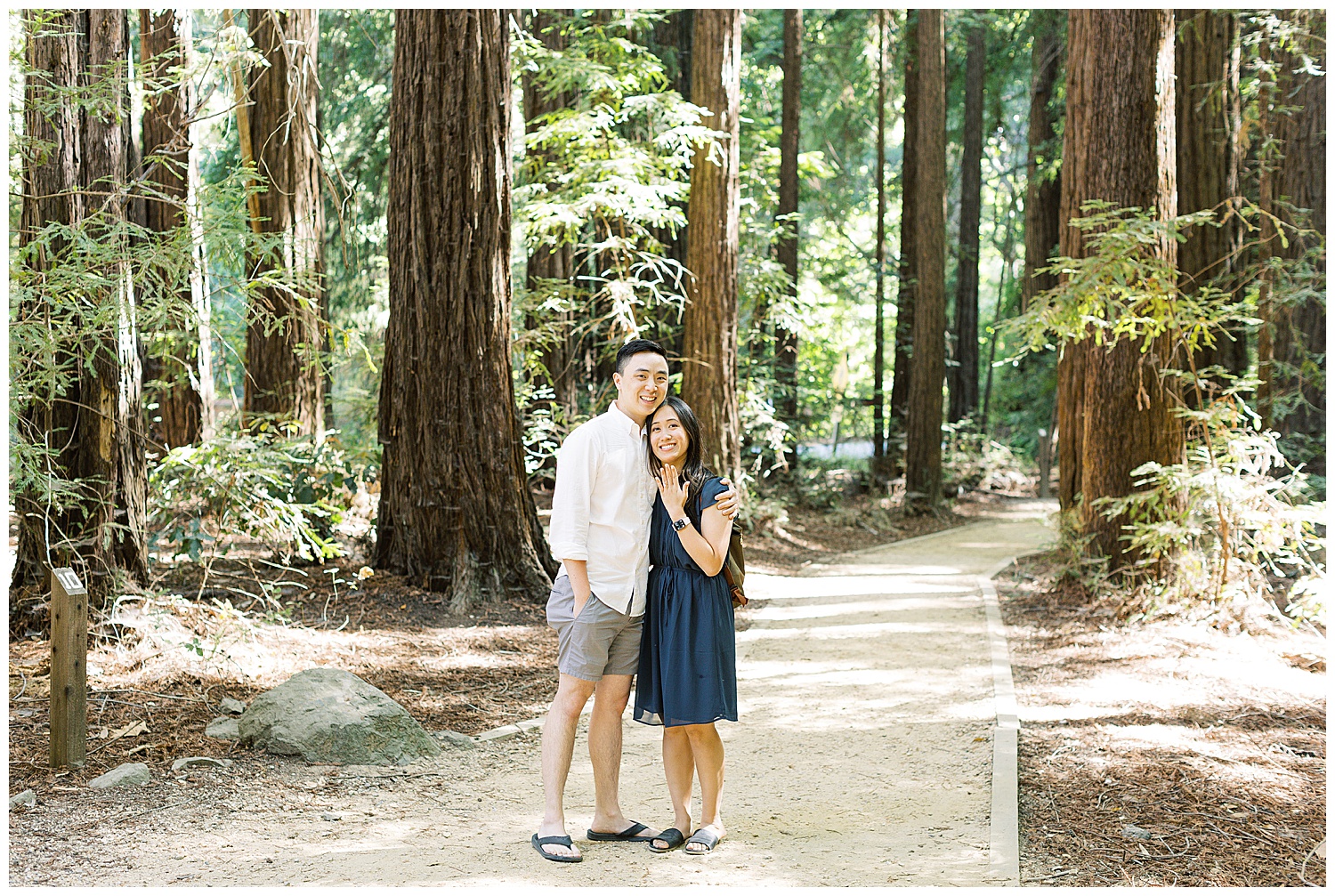 couple in redwood forest smiling at the camera