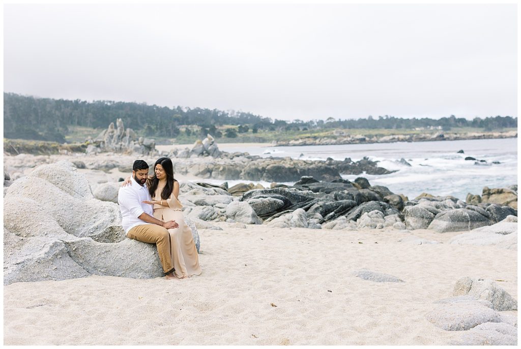 couple looking at their ring on the rocks at Carmel by the Sea during their surprise proposal