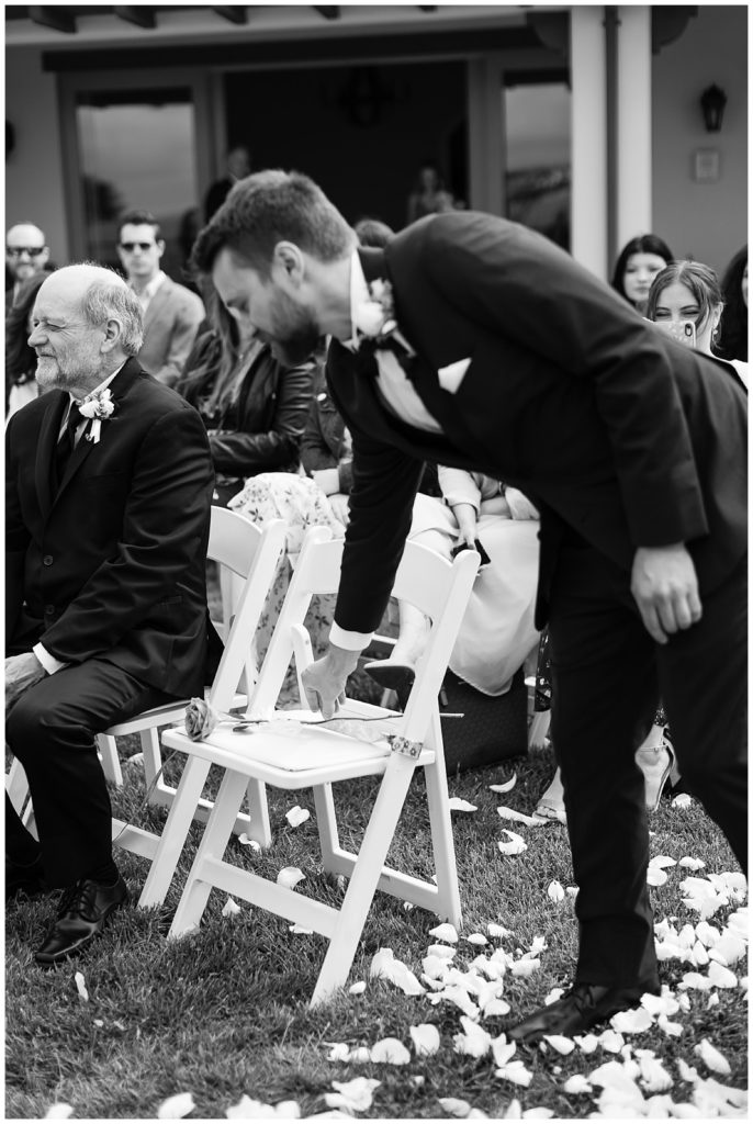 black and white portrait of the groom leaving a rose on his late mother's chair at his Intimate At-Home Wedding In Hollister by film photographer AGS Photo Art