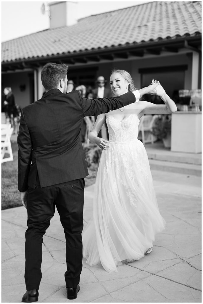 black and white wedding portrait of the groom twirling his bride