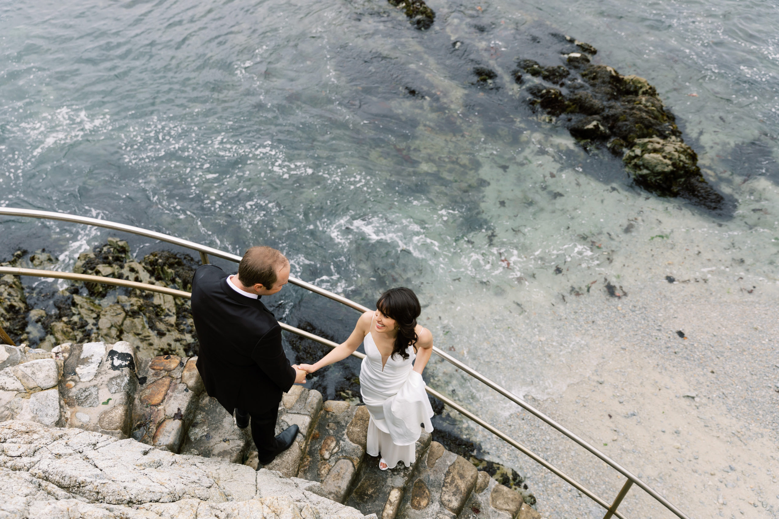 bride and groom on a stony staircase leading down to a private Carmel by the Sea beach for their First Look