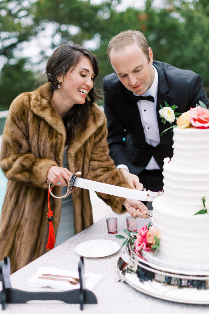 bride and groom cutting their Carmel by the Sea luxury wedding cake with a saber