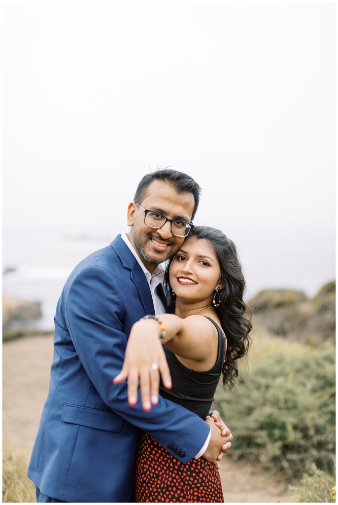 couple showing off their ring to the Big Sur photographer in celebration of their surprise proposal