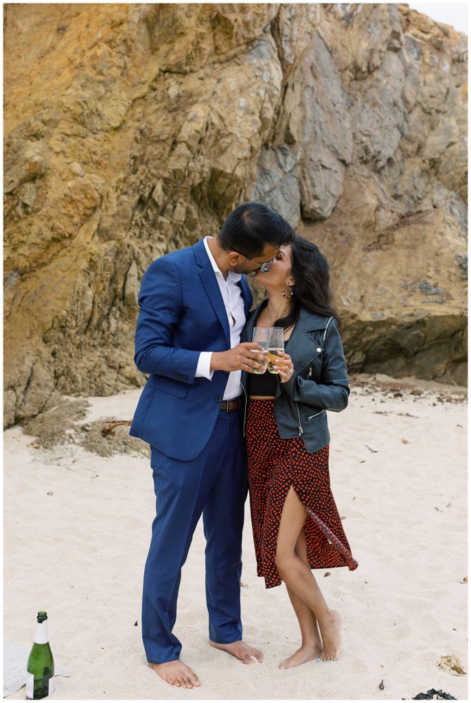 couple celebrating their Big Sur surprise proposal at the beach with champagne by film photographer AGS Photo Art