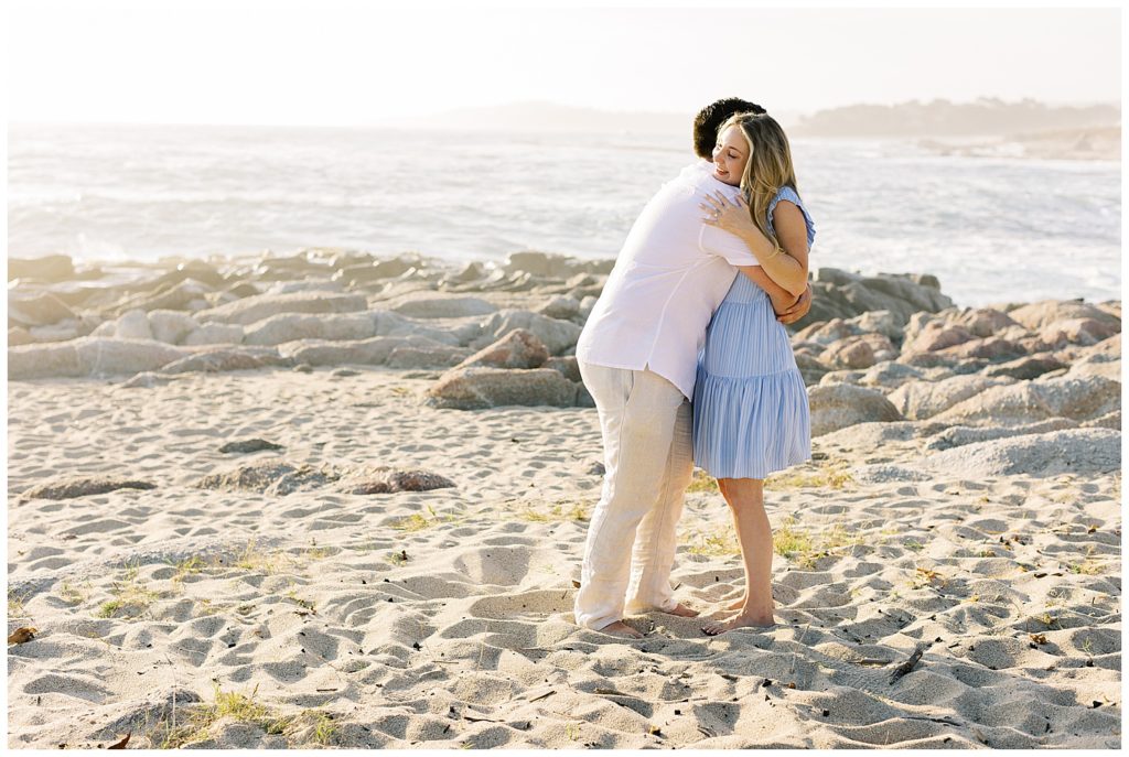 couple embracing each other at the beach after their surprise proposal in Carmel