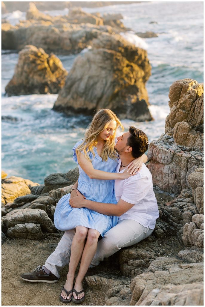 Carmel Beach portrait of the couple sitting on a rock in each other's laps by film photographer AGS Photo Art