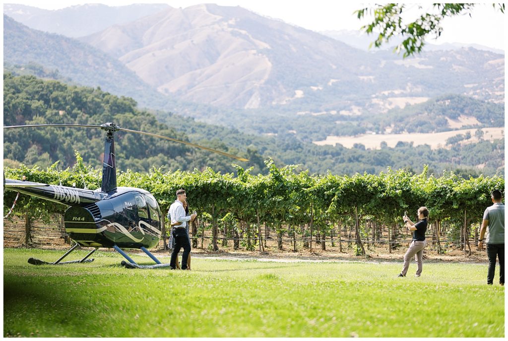 photo of couple in front of a helicopter at Joullian Winery for their surprise proposal in Carmel Valley by film photographer AGS Photo Art